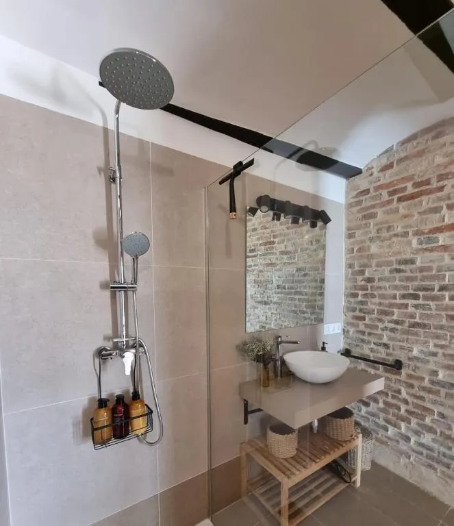 Rain shower with a glass screen and the brick wall reflected in the mirror