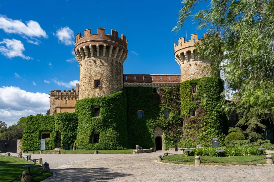 The front of Peralada Castle, with its two stone towers and green ivy covering the walls