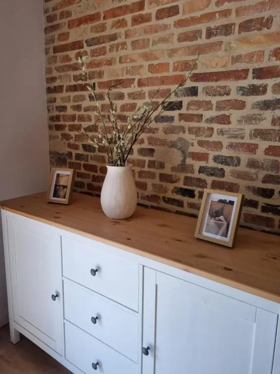Detail of the sideboard with a ceramic vase and photographs against the brick wall
