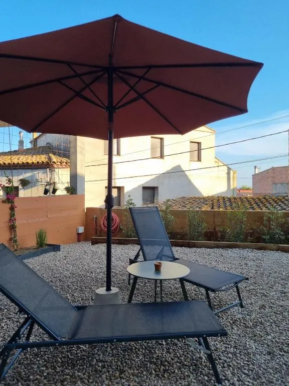 Two sun loungers and a red parasol on the gravel patio on a sunny day