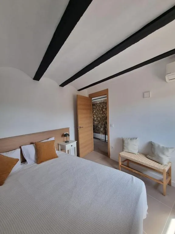 Double bedroom with a double bed, ochre cushions and black steel beams in the ceiling