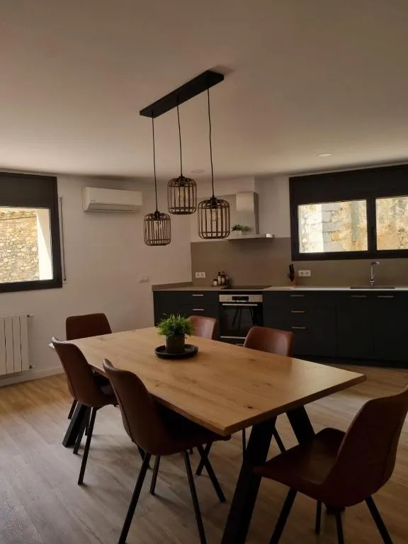 Solid wood table for six with wicker lamps and the kitchen behind