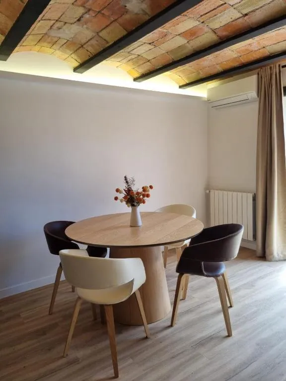 Round wooden table with four chairs under the Catalan vault, with indirect lighting