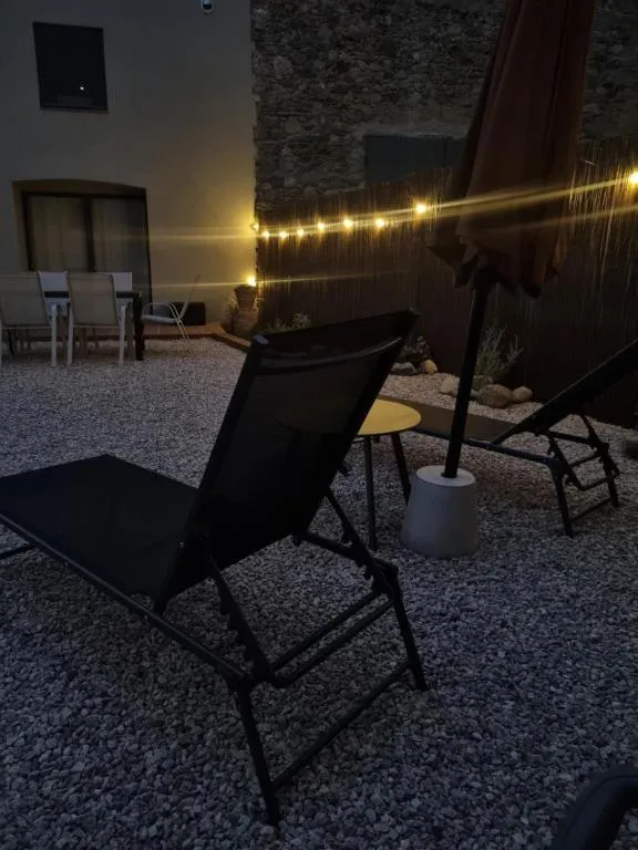 The patio at night, lit by garlands of warm light bulbs above the sun loungers