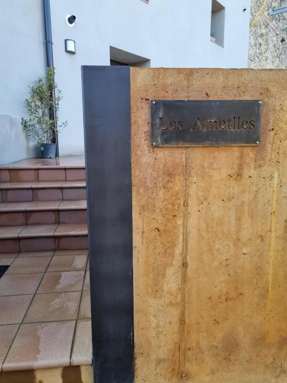 Brass sign reading “Les Ametlles” on the Corten steel wall at the entrance