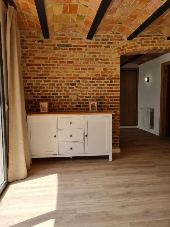 Living room with an old brick wall, tile vault and a white sideboard