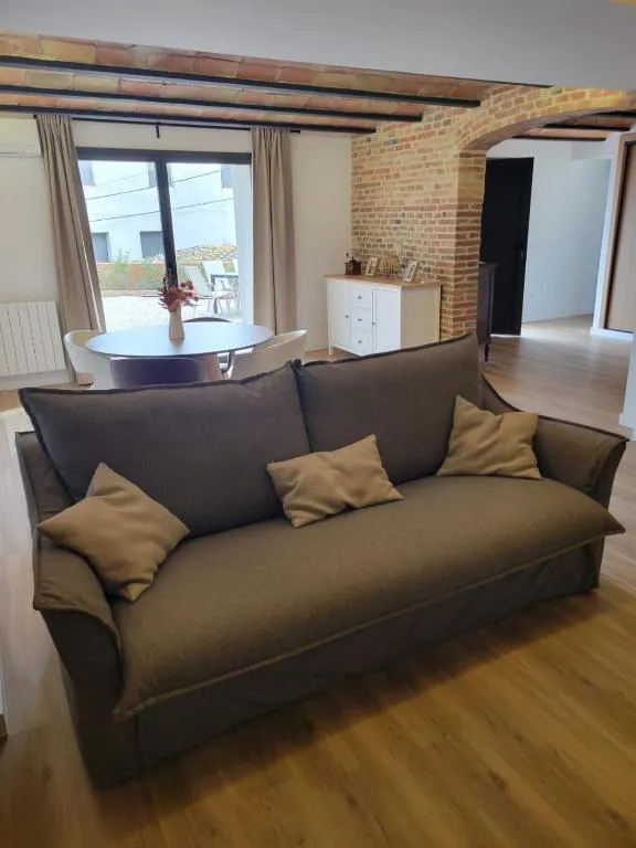 Large sofa in the living room beneath the exposed brick arch, with the dining area and the door to the patio behind