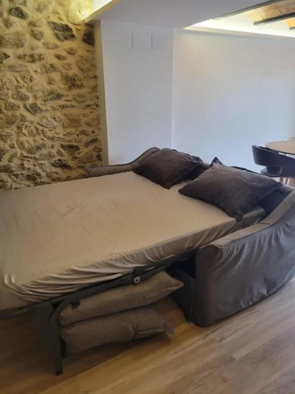 The sofa bed opened out, with the dry-stone wall lit up behind it
