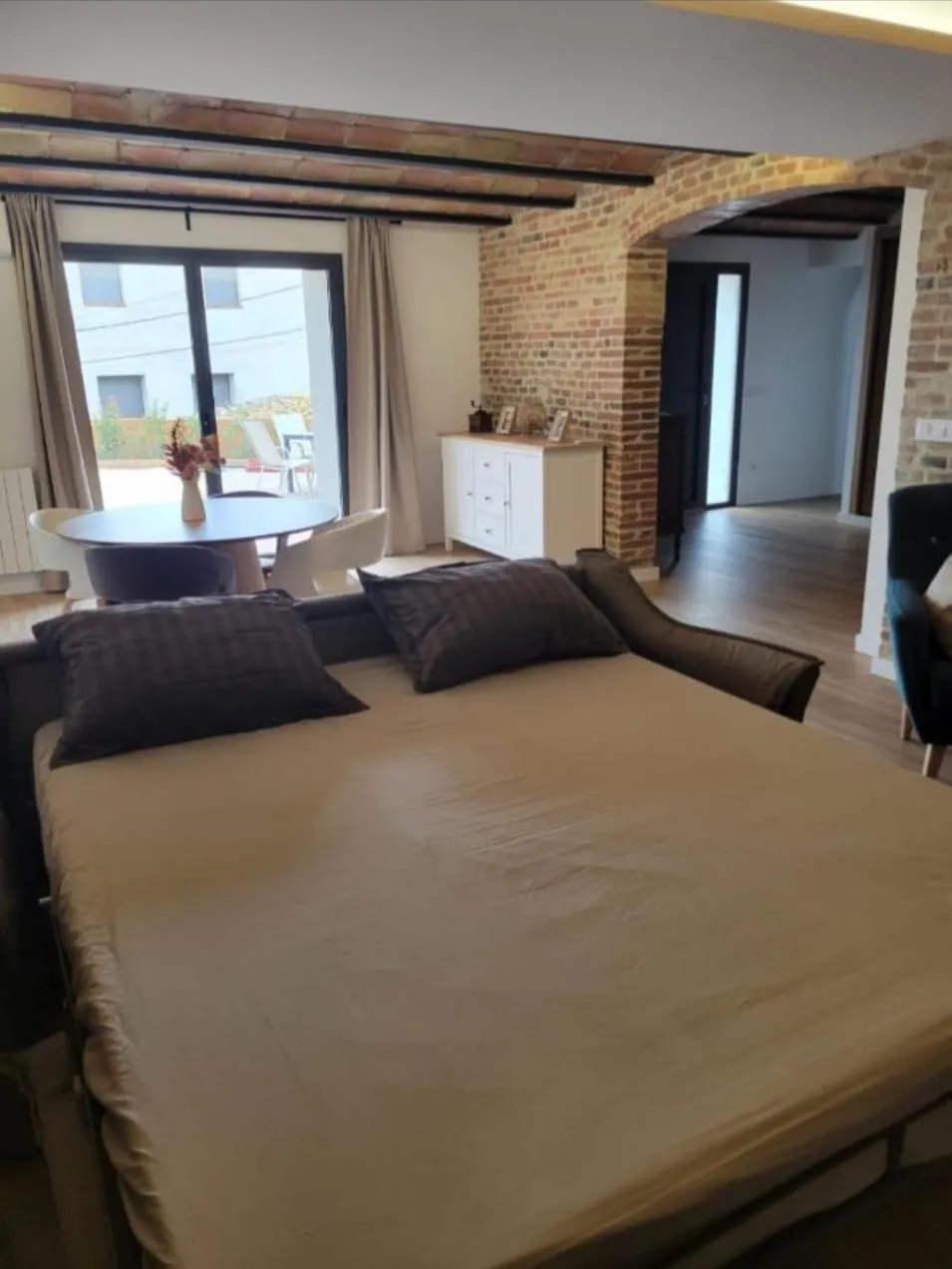 The living-room sofa bed opened and made up, with the brick arch and the exit to the patio behind