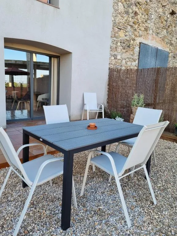Outdoor table with four chairs in front of the stone wall and the reed privacy screen
